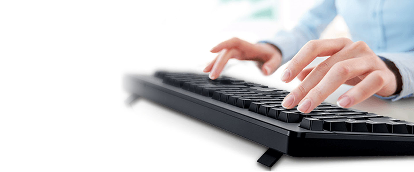 Primer plano de las manos de una persona tecleando en un teclado negro, con el fondo desenfocado.